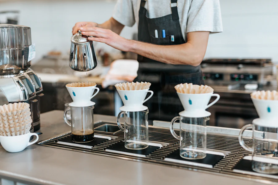 Barista pouring a row of pour-overs along the brew bar